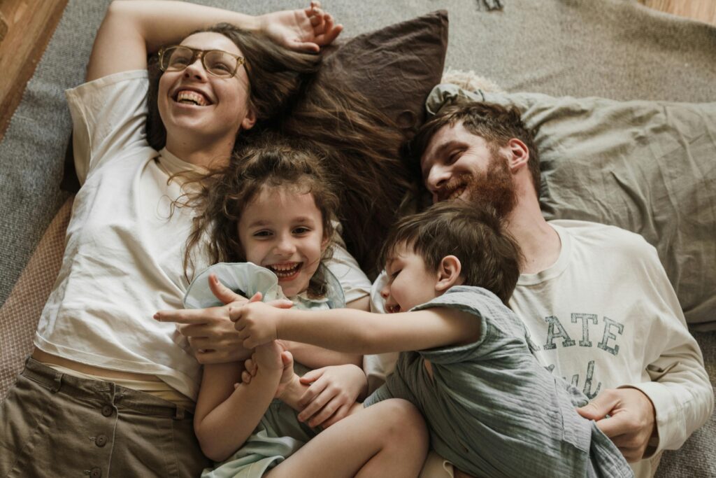 A joyful family bonding moment with children and parents lying together on a cozy bed.