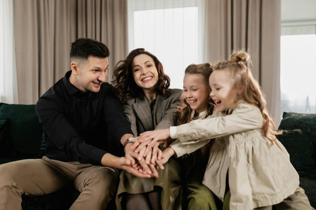 A cheerful family of four bonding together indoors with smiles and joy.